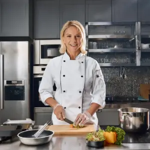 Joséphine, chef en cuisine, souriant(e) devant son plan de travail avec des ingrédients frais, prêt(e) à créer des recettes maison pleines de saveurs.