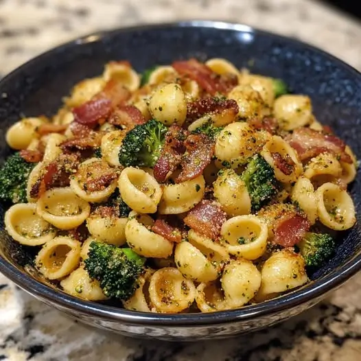 Un plat d'orecchiette épicées au brocoli et bacon, avec des couleurs vives et une texture invitante, servi dans une ambiance à faible luminosité.