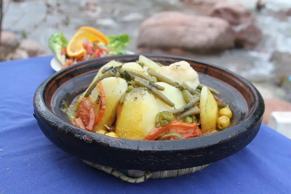 Image d'un tajine de légumes racines au millet avec des légumes frais comme des carottes, panais et patates douces, accompagné de millet et d'épices marocaines dans une ambiance chaleureuse.