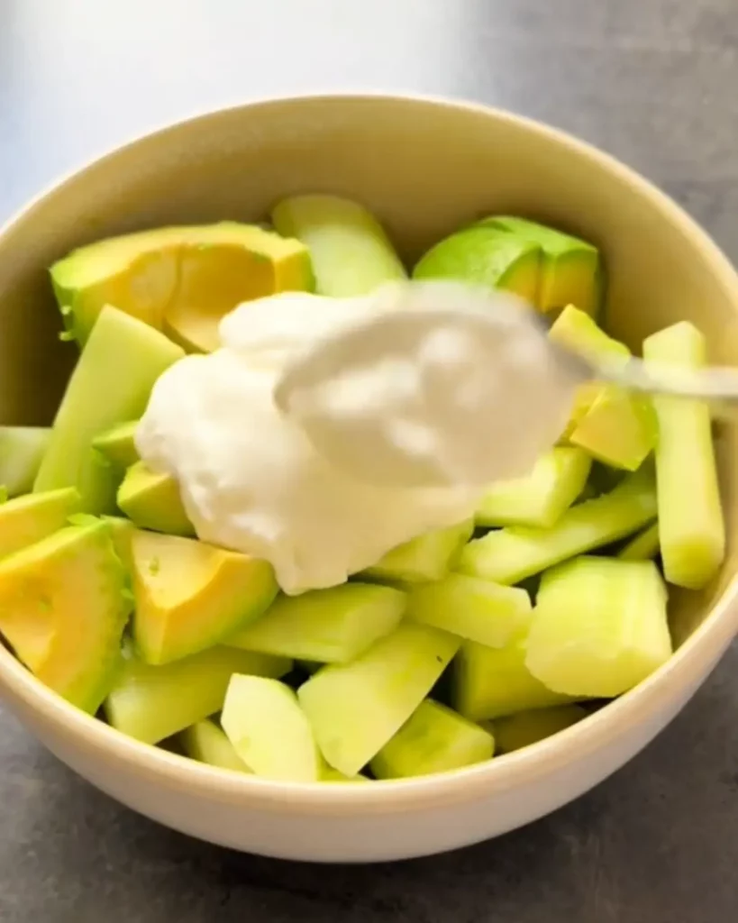 Blendeur mixant des dés de concombre et d’avocat avec du chèvre frais et de l’ail pour un gaspacho onctueux