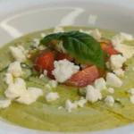 Verrine de gaspacho vert concombre-avocat, garnie de pignons de pin et saupoudrée de paprika.